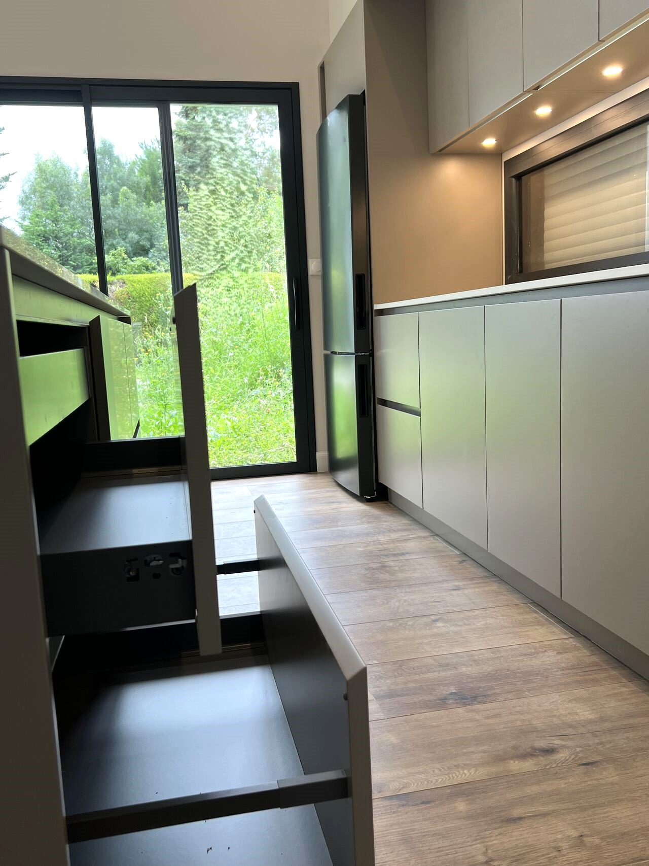 Façades Sahara laqué mat sans poignées, éclairage sous meubles hauts et rangement sur mesure dans une cuisine ARMONY CUCINE.