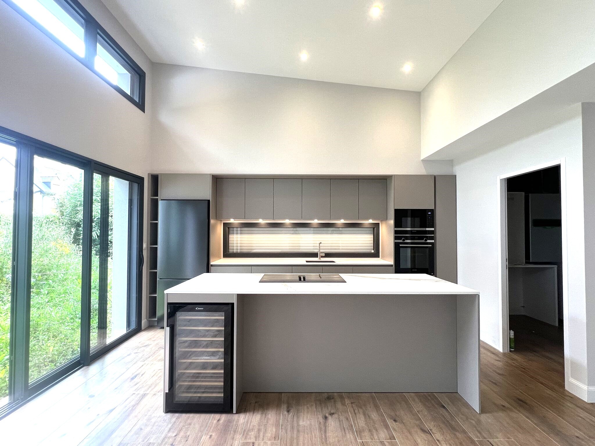 Ilot central avec plaque induction aspirante Siemens et cave à vin encastrée dans une cuisine design à Sucé-sur-Erdre.