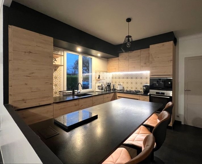 Cuisine italienne haut de gamme Armony Cucine installée à Grandchamps-des-Fontaines par Cuisines de l’Erdre, avec façades en bois chêne, plans de travail en granit noir satiné, îlot central et électroménagers encastrés.