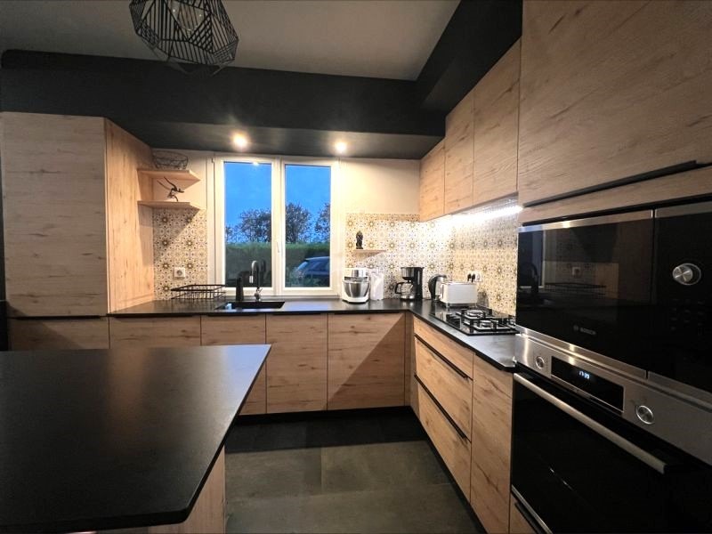 Cuisine aménagée avec meubles encastrés, électroménagers intégrés, îlot central et éclairage LED, installée par Cuisines de l’Erdre en Loire-Atlantique
