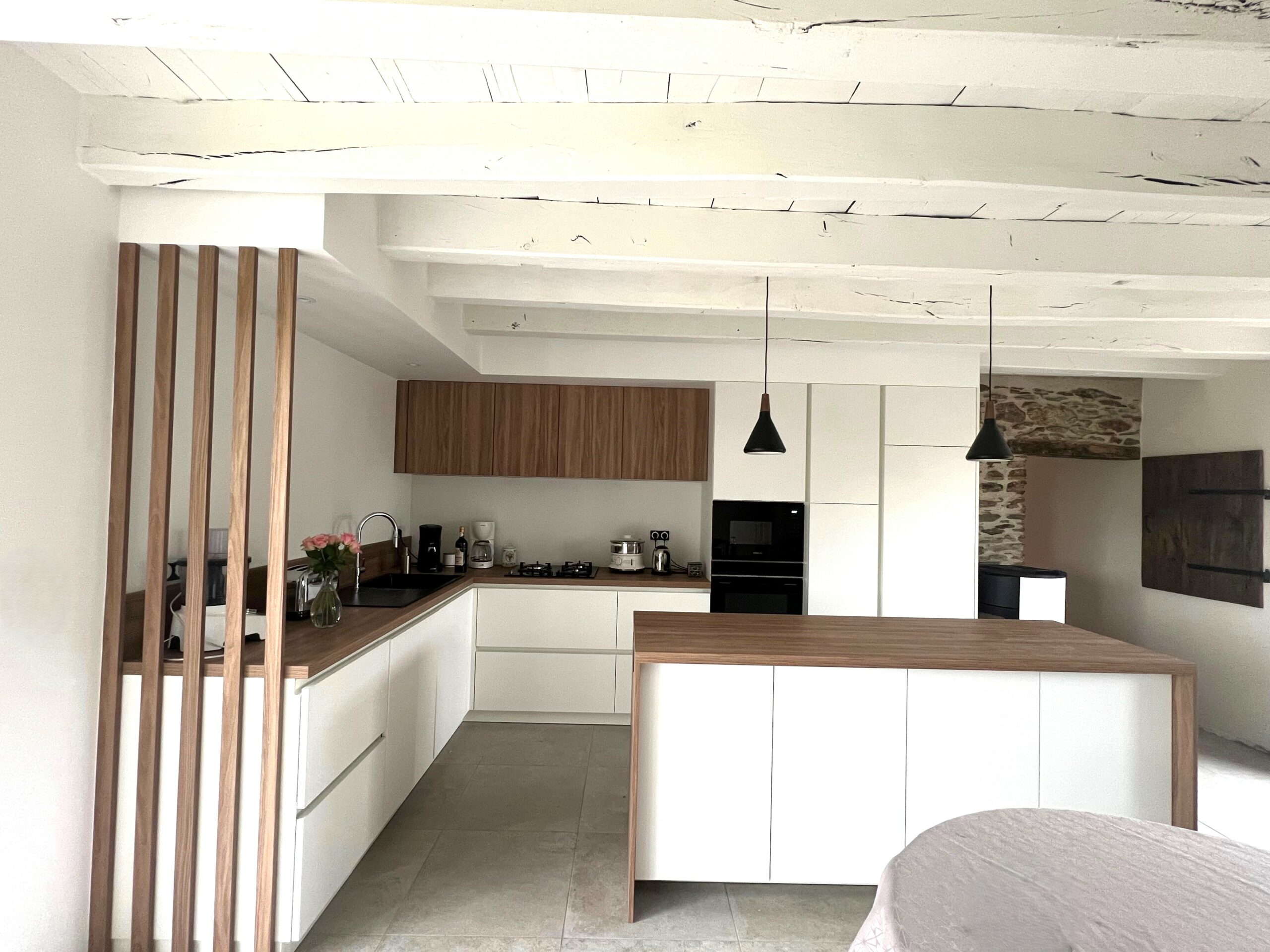 Aménagement de cuisine Armony Cucine sur mesure à Sucé-sur-Erdre, avec des colonnes encastrées, une plaque de cuisson au gaz et un meuble bas en bois naturel.