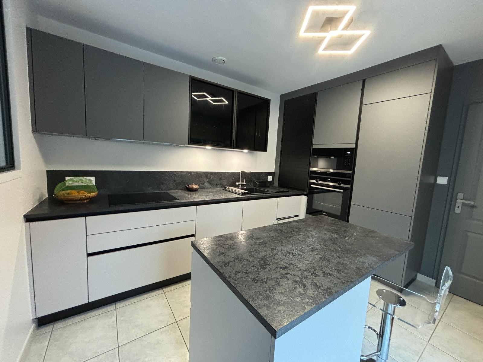 Cuisine semi-ouverte à Sucé-sur-Erdre avec verrière noire et électroménagers intégrés Armony Cucine.