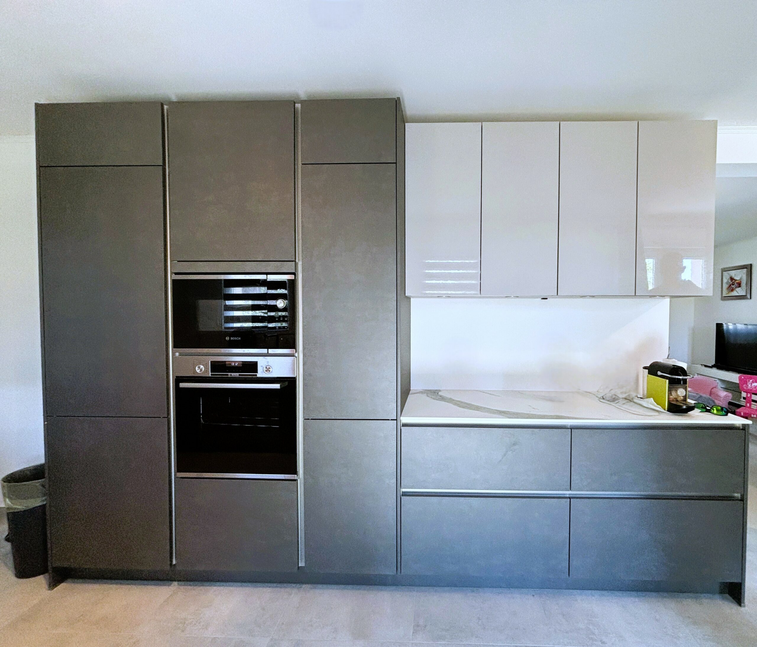 Colonnes encastrées avec four, micro-ondes et réfrigérateur intégrés dans une cuisine ARMONY CUCINE à Ligné, finition laquée brillante gris clair.