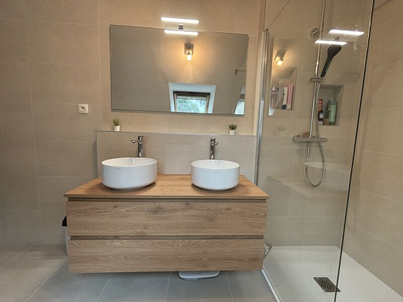 Salle de bain haut de gamme à La Chapelle-sur-Erdre avec meuble suspendu en bois Kios et douche à l'italienne avec carrelage travertin.