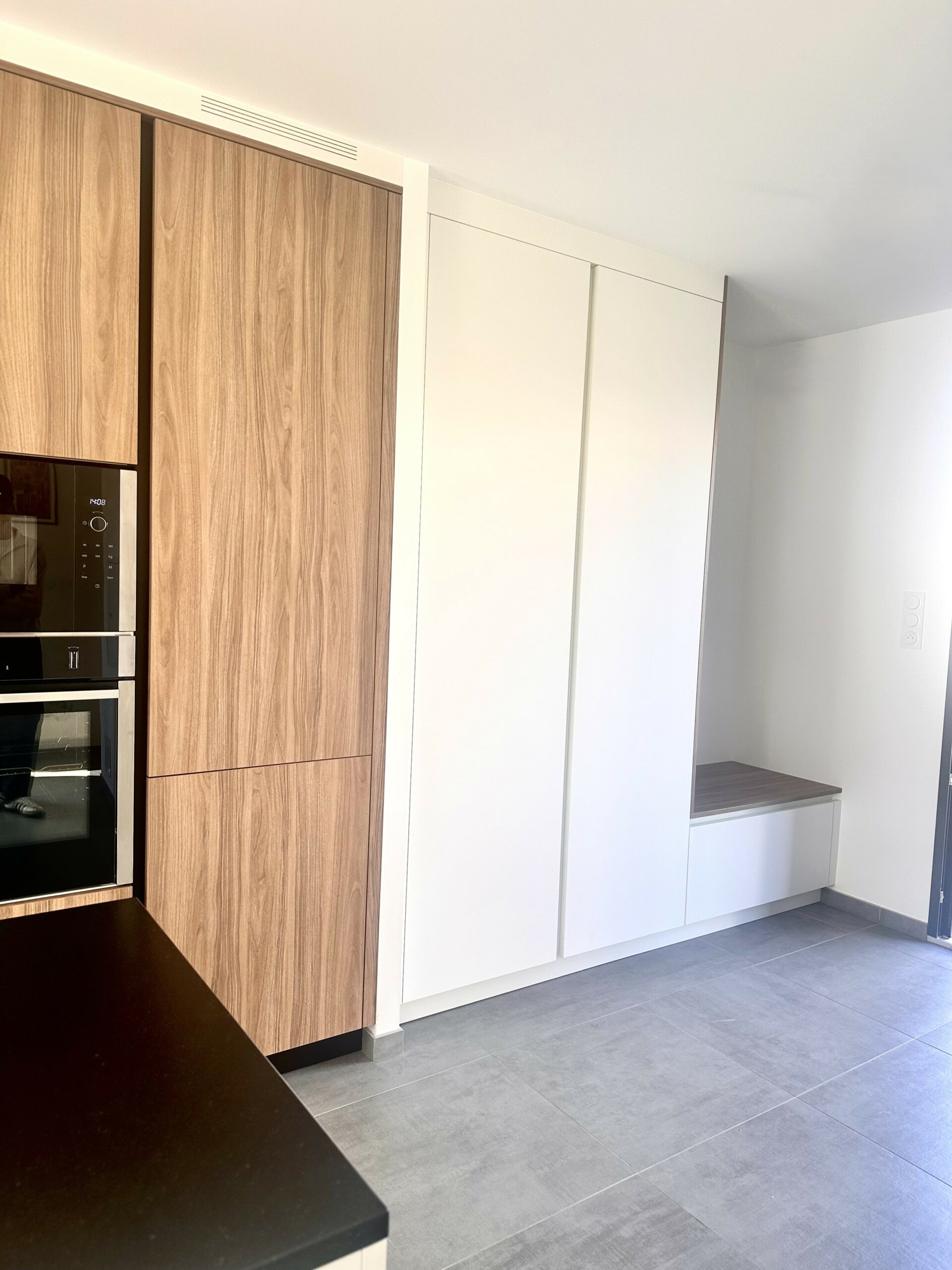 Aménagement d'entrée sur mesure avec banc et colonnes de rangement blanches à Sucé-sur-Erdre.