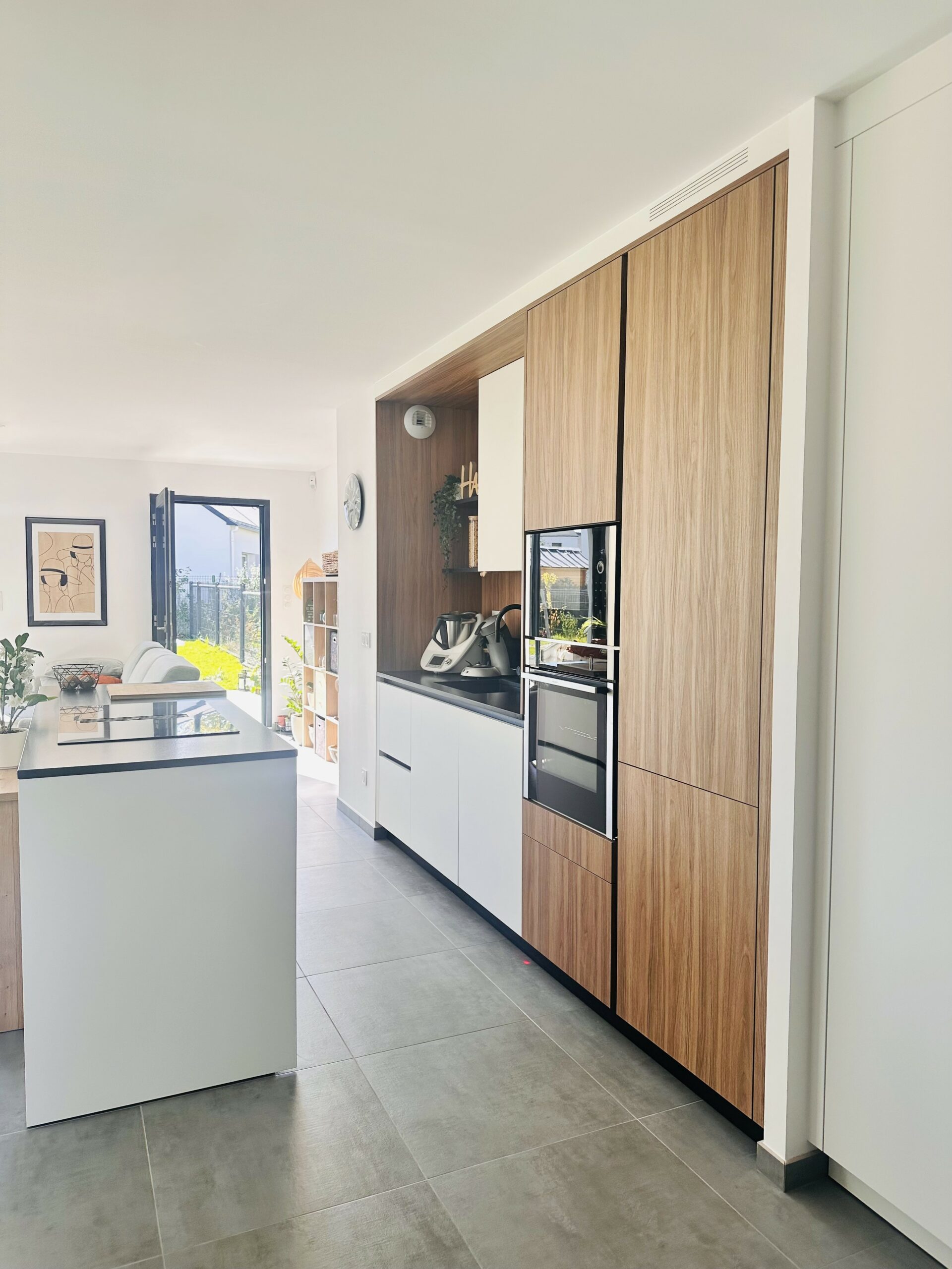 Cuisine contemporaine blanc mat et bois avec plan de travail en granit noir du Zimbabwe à Sucé-sur-Erdre.