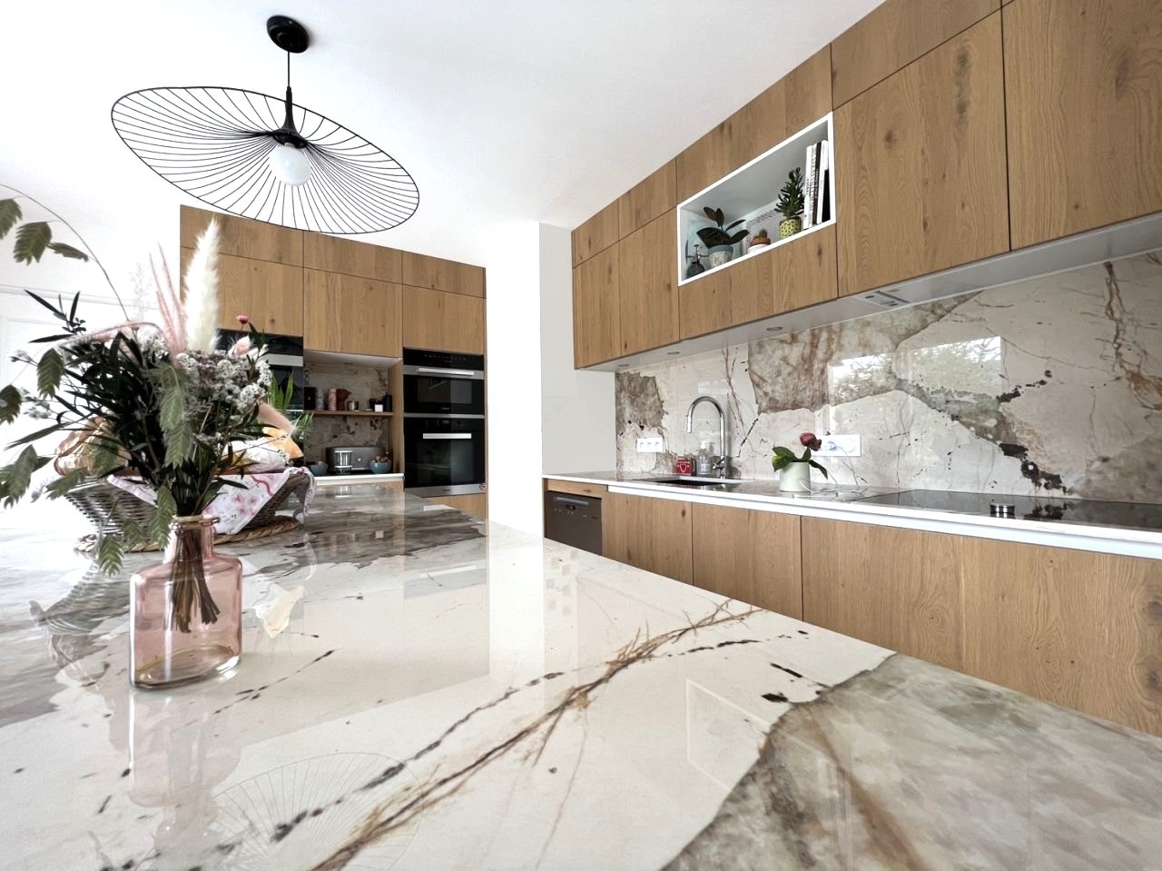 Cuisine contemporaine Armony Cucine avec façades bois et plan de travail en Dekton Khalo installée à Sucé-sur-Erdre.