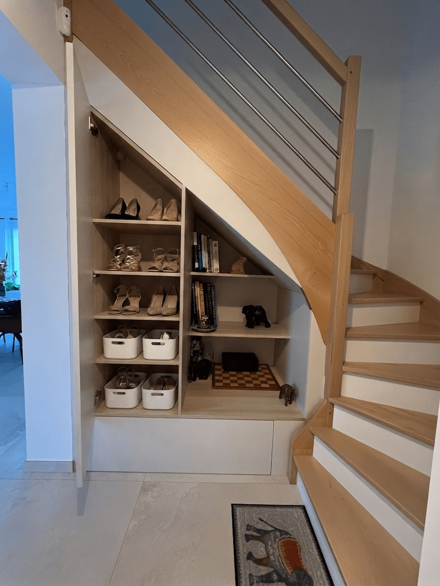 Aménagement sous escalier sur mesure dans une entrée à La Chapelle-sur-Erdre avec façades beige sable et étagères bois réalisé par Cuisines de l'Erdre